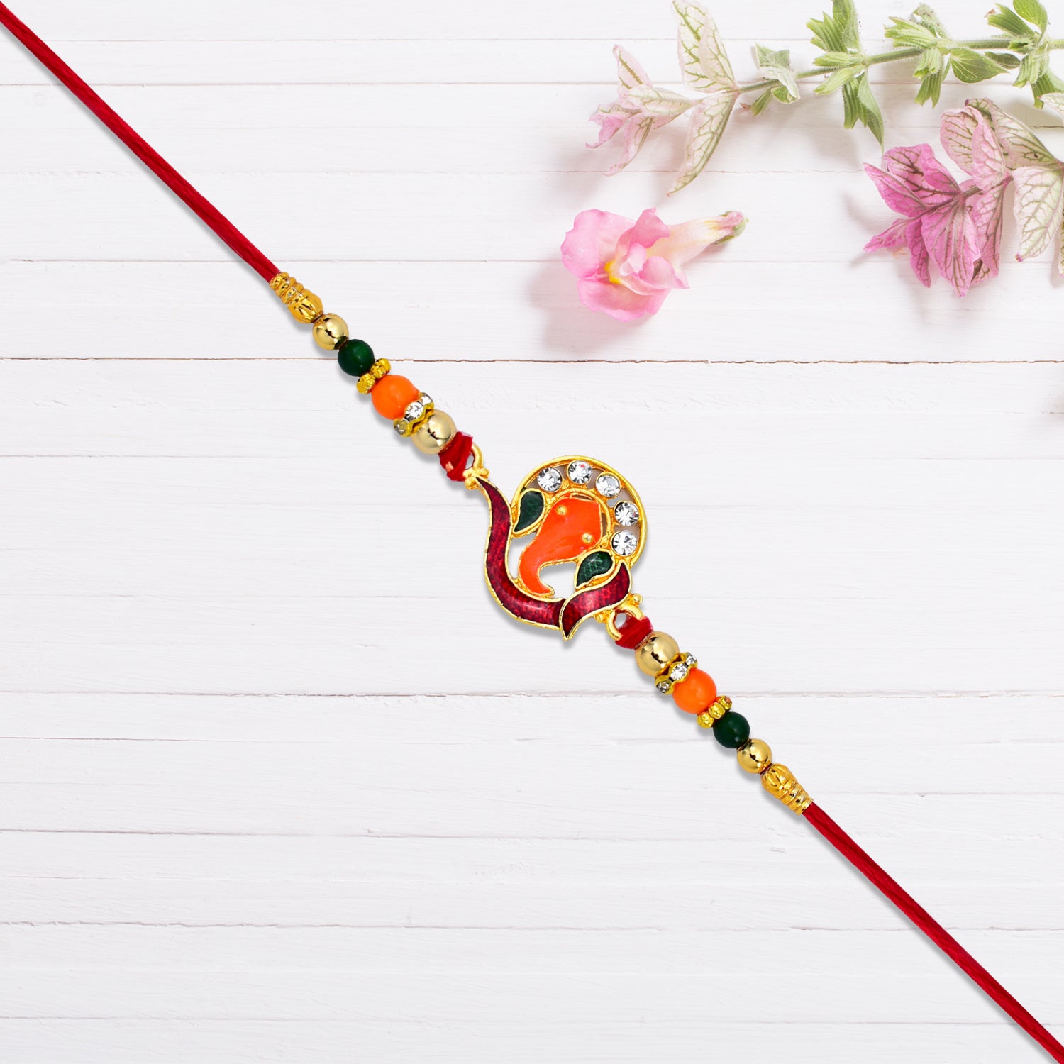 Golden Ganesha Rakhi With Red-green Beads And Stone Detailing Golden Ganesha Rakhi With Red-green Beads And Stone Detailing